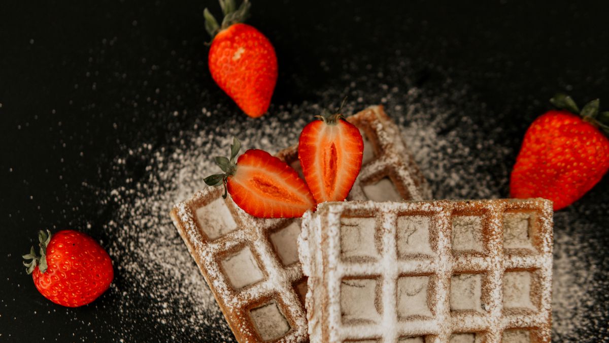 Belgian waffle topped with fresh strawberries and powdered sugar
