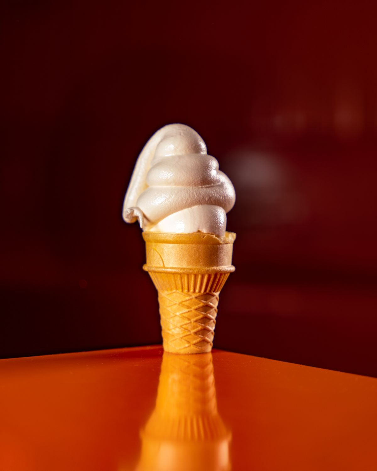 A swirled soft-serve ice cream cone against a dark background