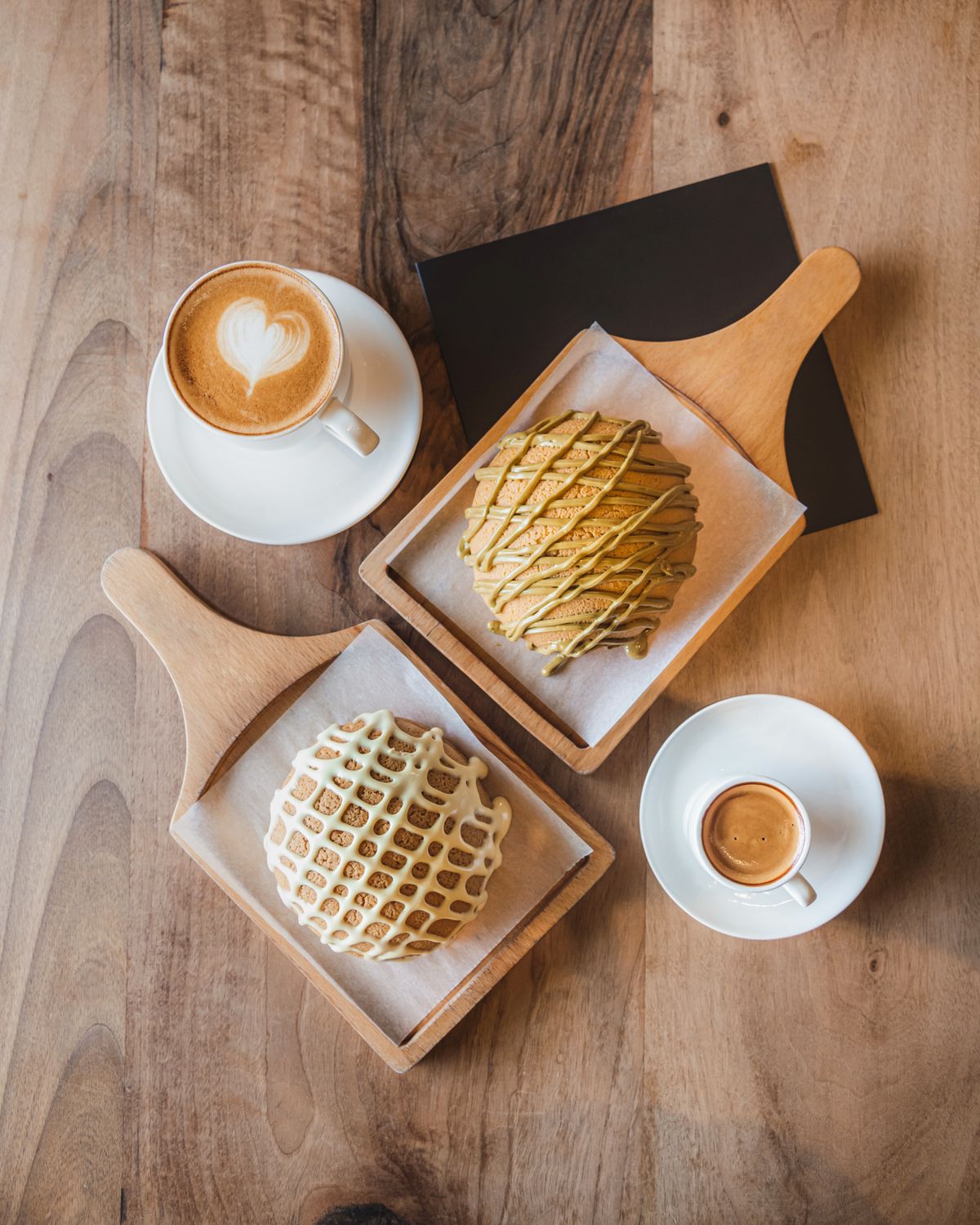 Espresso drinks and fresh-baked pastries on a wooden table